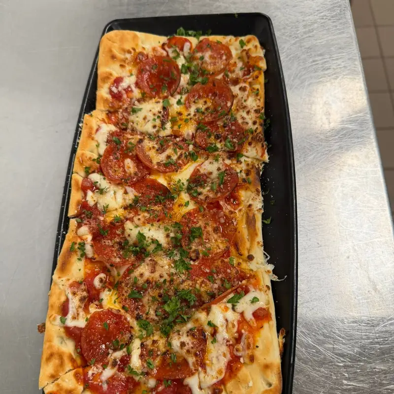 Pepperoni flatbread pizza fresh from the oven, dusted with parmesan and parsley