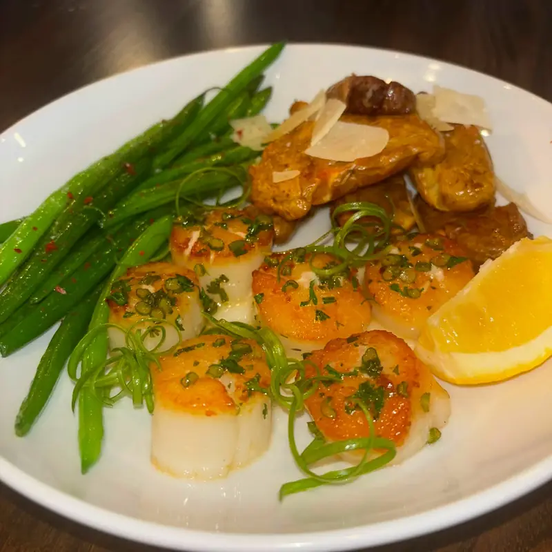Pan-seared scallops with charred green beans, shaved parmesan and a lemon wedge