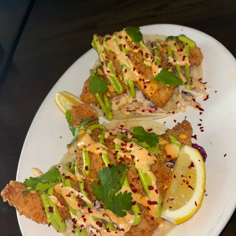 Crispy fish tacos with slaw, avocado crema, chili-spiced aioli and cilantro